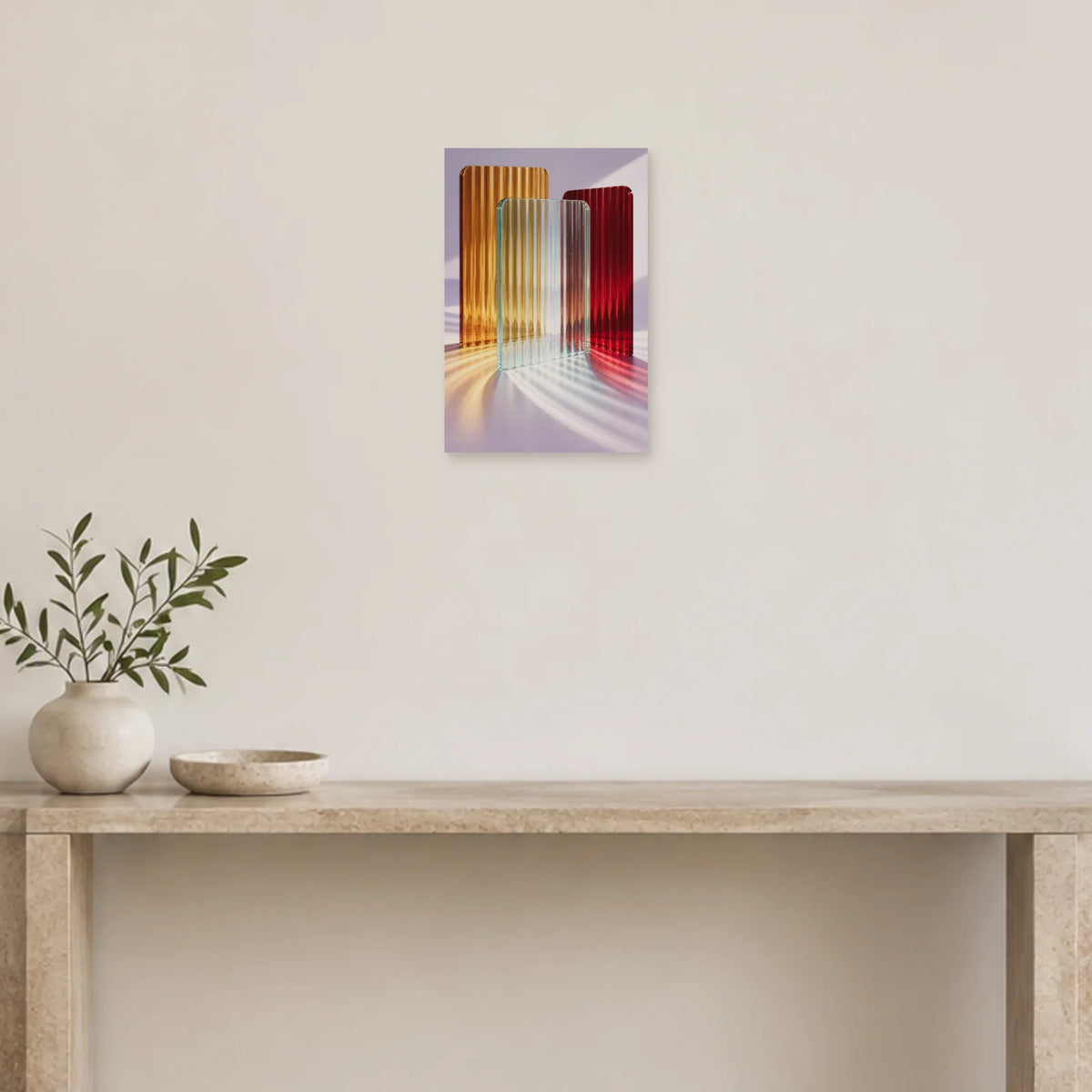 Riffelglas-Poster mit bernstein-, rubin- und aquafarbenen Platten und farbigem Licht auf Lavendel über einer hellen Konsole mit einer Vase voller belaubter Zweige