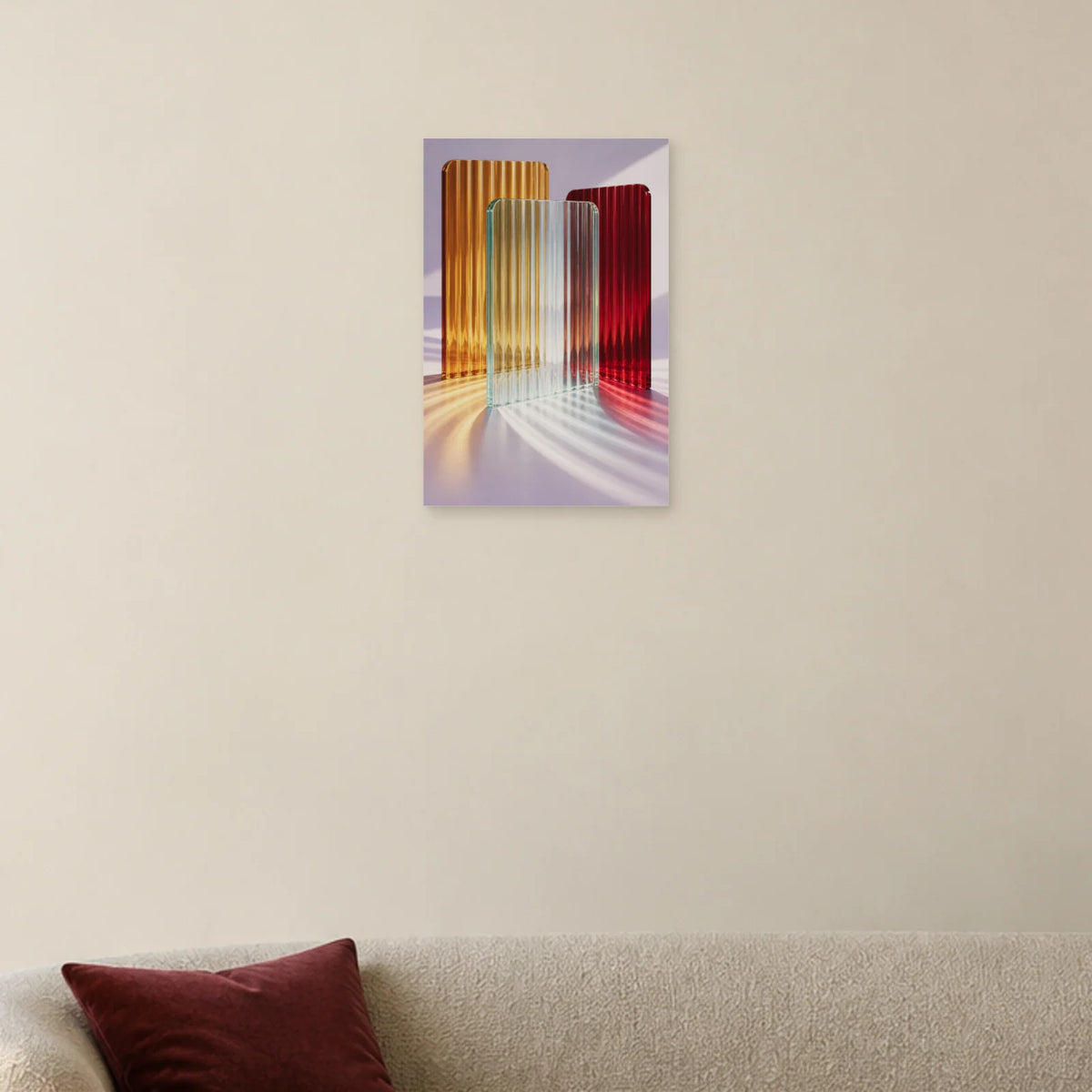 Riffelglas-Poster mit bernstein-, rubin- und aquafarbenen Platten und farbigem Licht auf Lavendel über einem hellen Sofa mit bordeauxrotem Kissen
